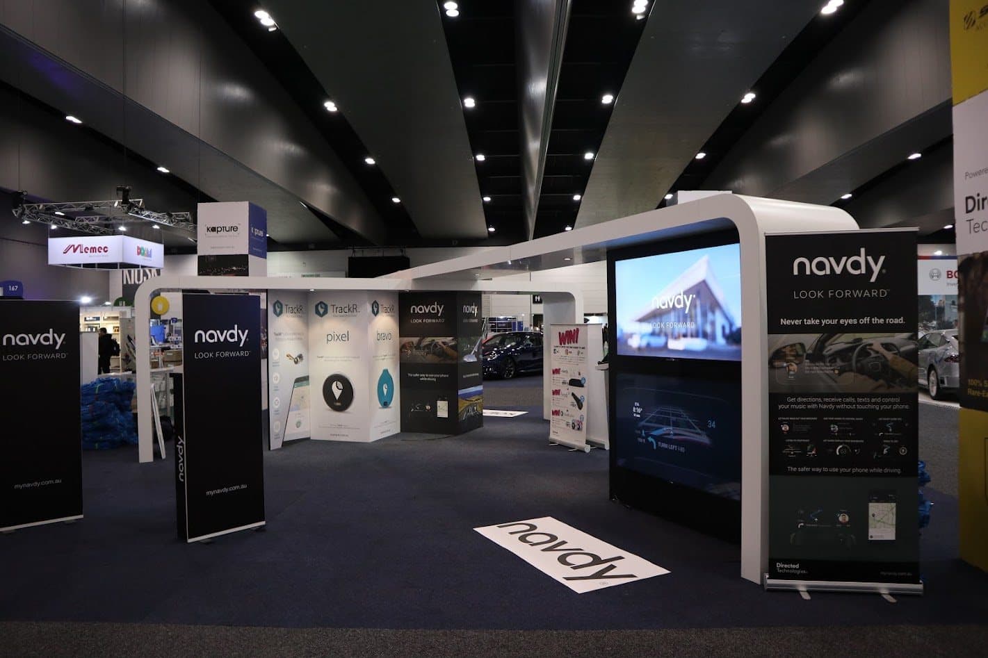 Navdy exhibition stand with product banners and a large screen showing the head-up display